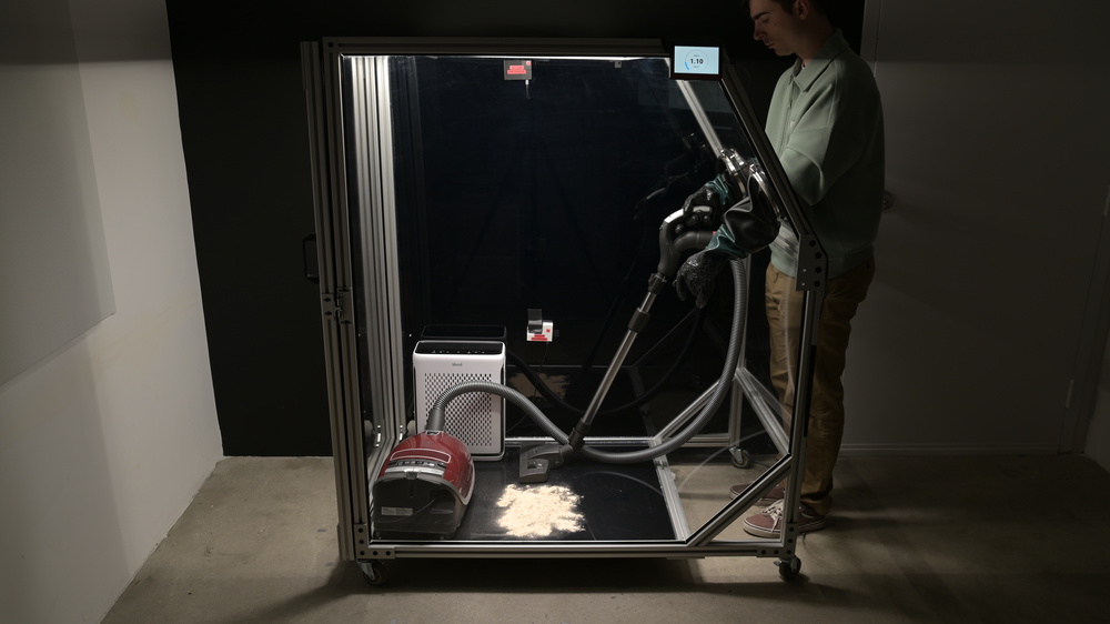 A large transparent test chamber, nearly the height of a person. The person operates the vacuum inside the chamber using arm-length gloves built into the chamber.