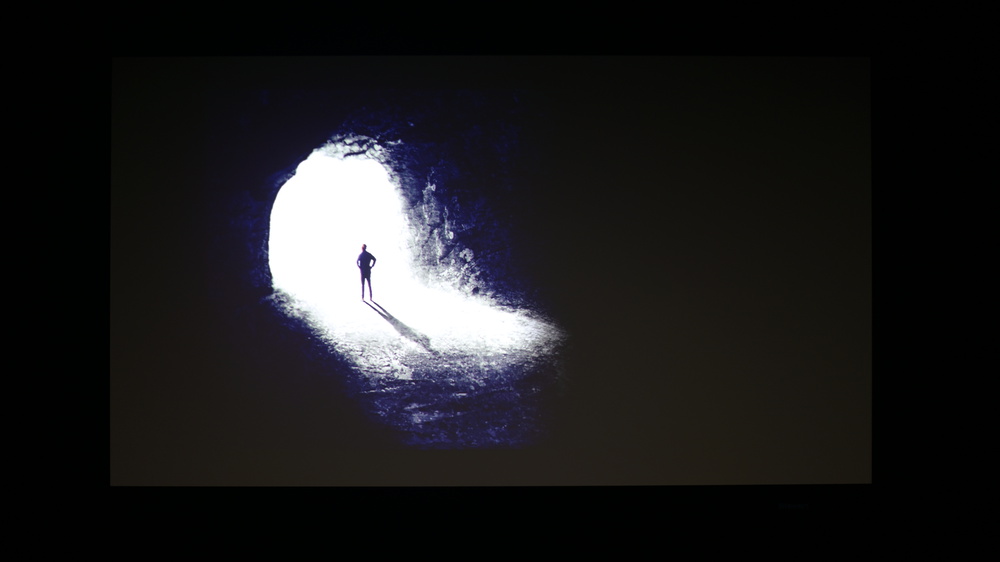 A picture of a contrast test pattern featuring a man at the bright entrance of a very dark cave.