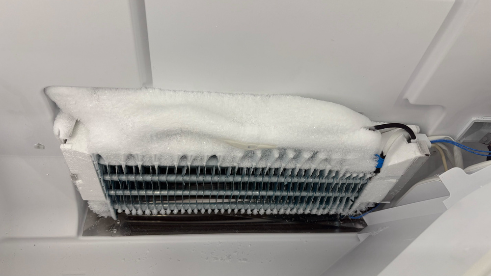A solid layer of frost several inches thick covers the top of a metal evaporator.
