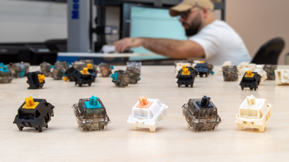 A photo showing five mechanical switches in the foreground, with many more in the background.