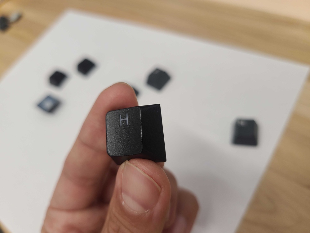 A close-up of a black double-shot PBT keycap from the Wooting 80HE, with the letter 