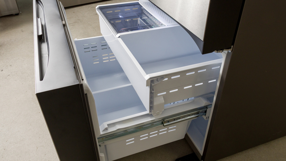 The bottom pull-out drawer freezer section of a French door refrigerator. The entire panel is the front of a large pull-out drawer. Inside is a separate, medium-height pull-out drawer separated into an ice tray on the left and a bin on the right. Underneath is a large bin separated by a divider.