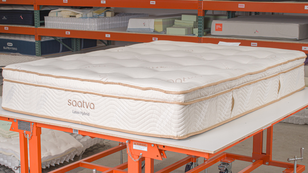 The Saatva Latex Hybrid, a very responsive mattress, on a table in a warehouse setting.
