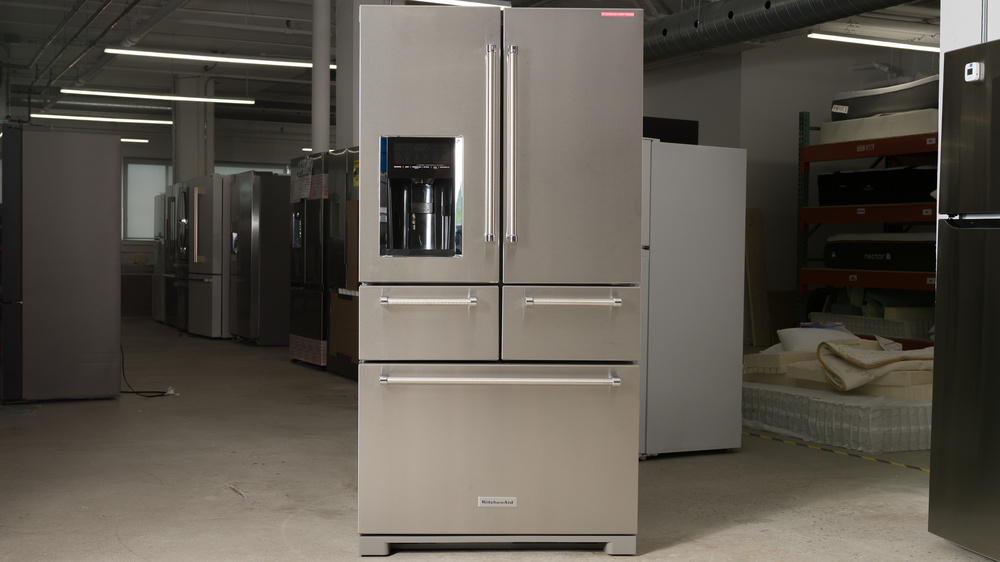 A stainless steel refrigerator, divided into two doors on top, two pull-out drawers underneath, and a pull-out freezer drawer below. There's an ice and water dispenser recess at the bottom of the left fridge door and handles on every compartment surface.