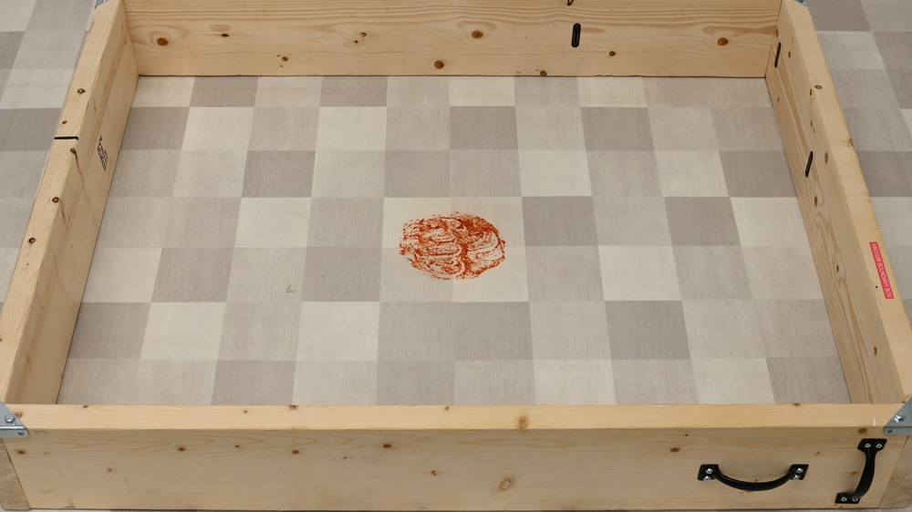 A heavy stain on a floor in a wooden box.