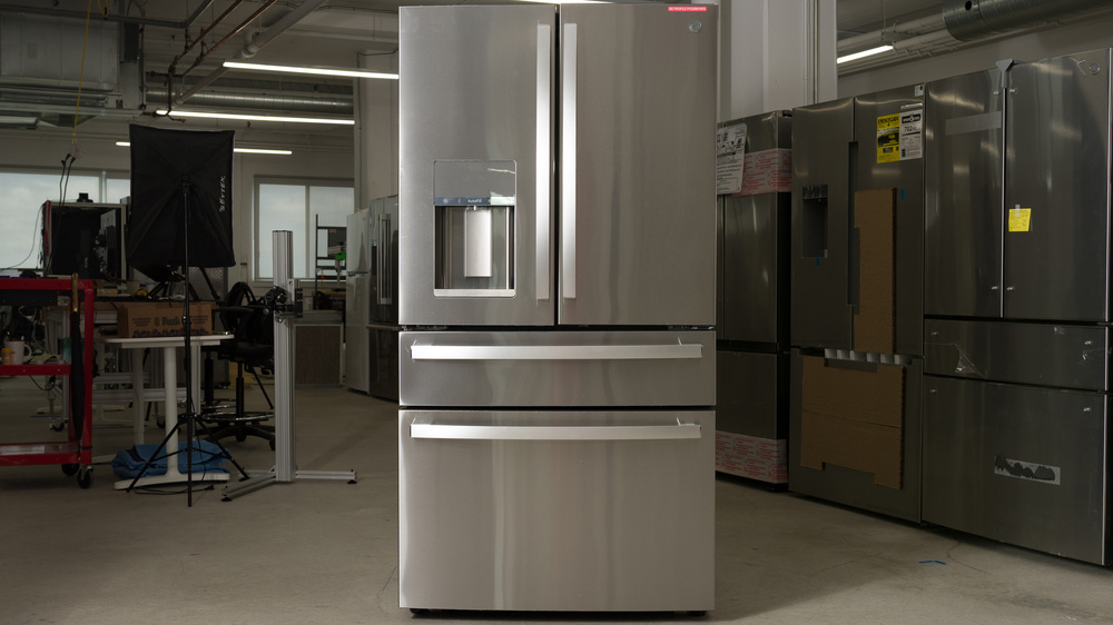 A stainless steel refrigerator, divided into two doors on top, a single full-width pull-out drawer underneath and a pull-out freezer drawer below. There's an ice and water dispenser recess at the bottom of the left fridge door and handles on every compartment surface.