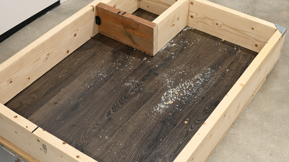Our hard floor pickup test setup, which is built out of wood. Inside the testing area, debris left from the bObsweep Dustin can be seen, including whole pieces of cereal and significant amounts of rice and sand.
