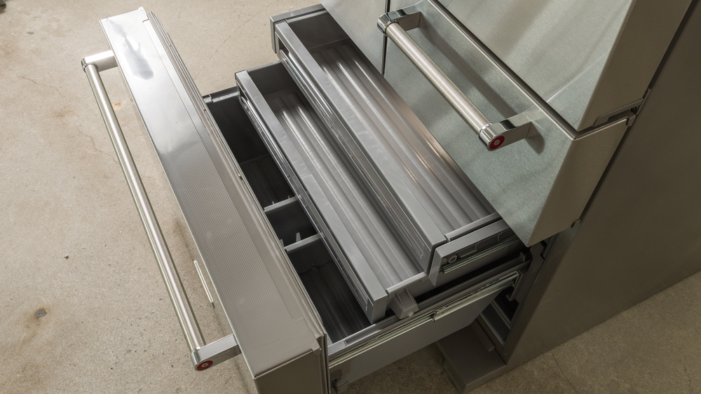 The freezer section of a 5-door refrigerator, which is a pull-out drawer with two short pull-out drawers inside. There are three deeper bins at the bottom with two dividers in between.