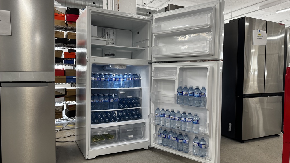 A top freezer refrigerator with the fridge and freezer doors open. The doors are the full width of the fridge compartment and are very wide.