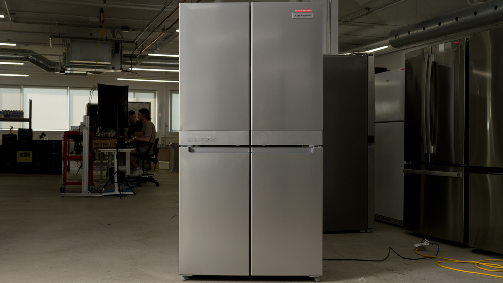 A stainless steel refrigerator with two doors on the upper refrigerator section and two doors on the lower freezer section. There are no handles, instead there's a finger recess carved out of the top of the freezer section.