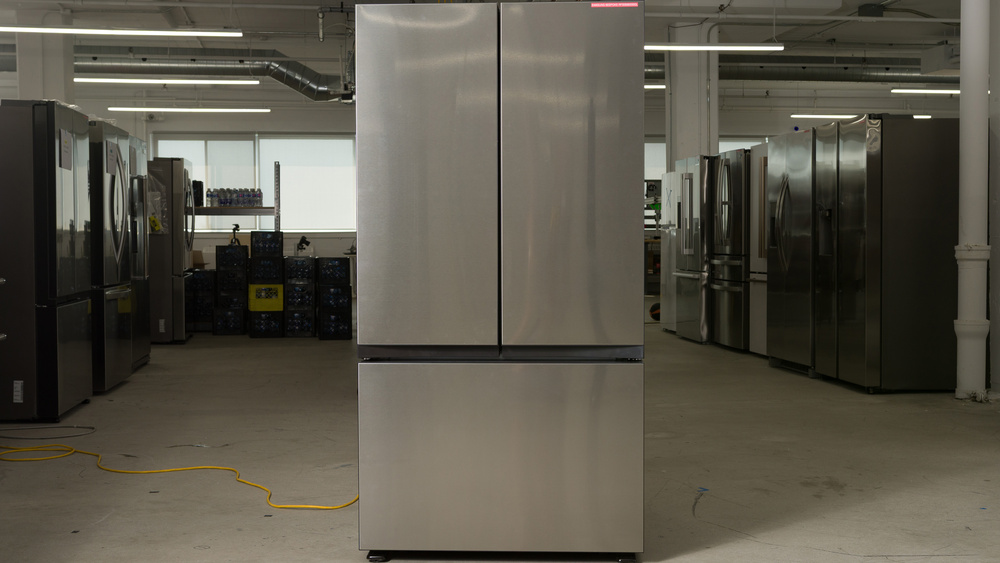 A French door-style refrigerator in a stainless steel finish. There are two doors on the top, split down the center, and a full-width freezer section below.