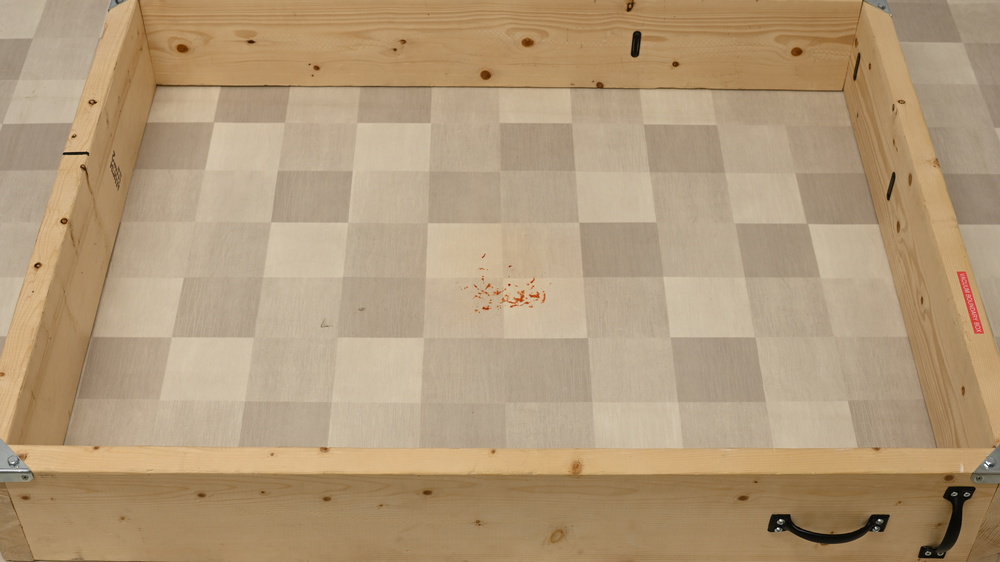 Small remnants of a stain left on a floor inside a wooden box.