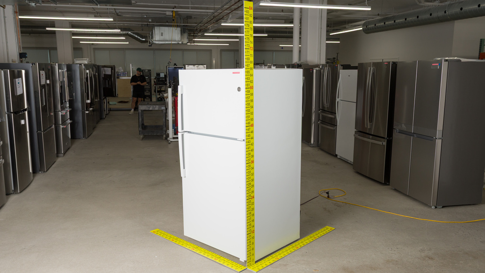 A white refrigerator with dimensioned sticks positioned to measure width, depth and height. Width is between 32" and 33", depth is between 34" and 35", and height is 66".