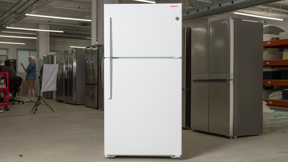 A white refrigerator, with a top freezer door spanning the upper third of the compartment, and a main door underneath extending about two thirds up the refrigerator. There are handles on both doors on the left.