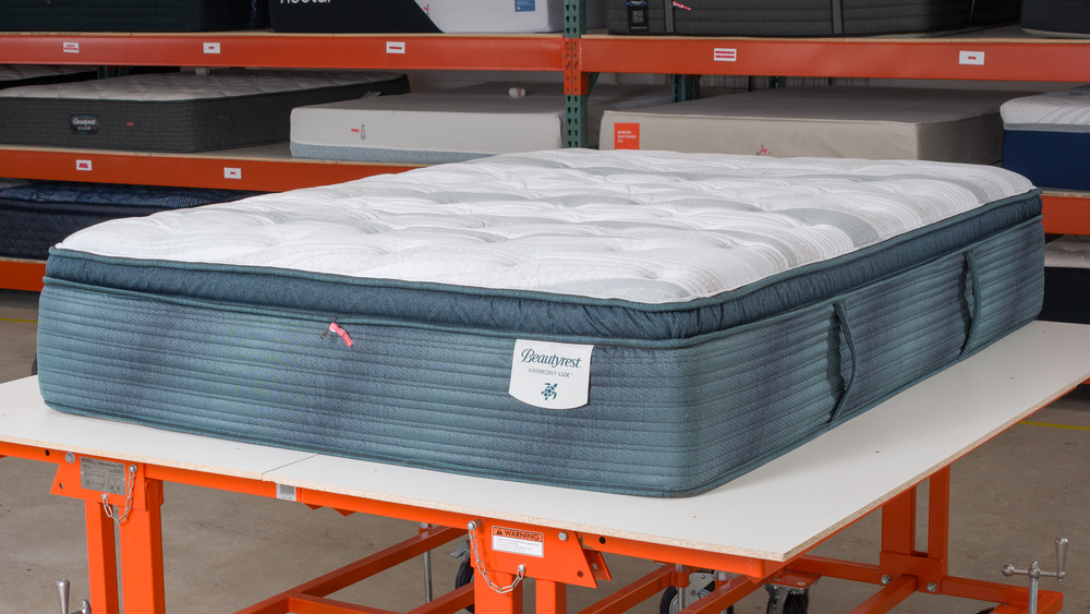  The Beautyrest Harmony Lux, a hybrid mattress with great motion isolation, on a table in a warehouse setting.